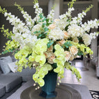 Grand Palais Premium permanent floral arrangement in the Pistachio Garden palette, displayed in the exclusive Grand Palais Bowl finished in Onyx Shimmer, featuring soft green orchids, cream roses, white hydrangeas, and white delphiniums.