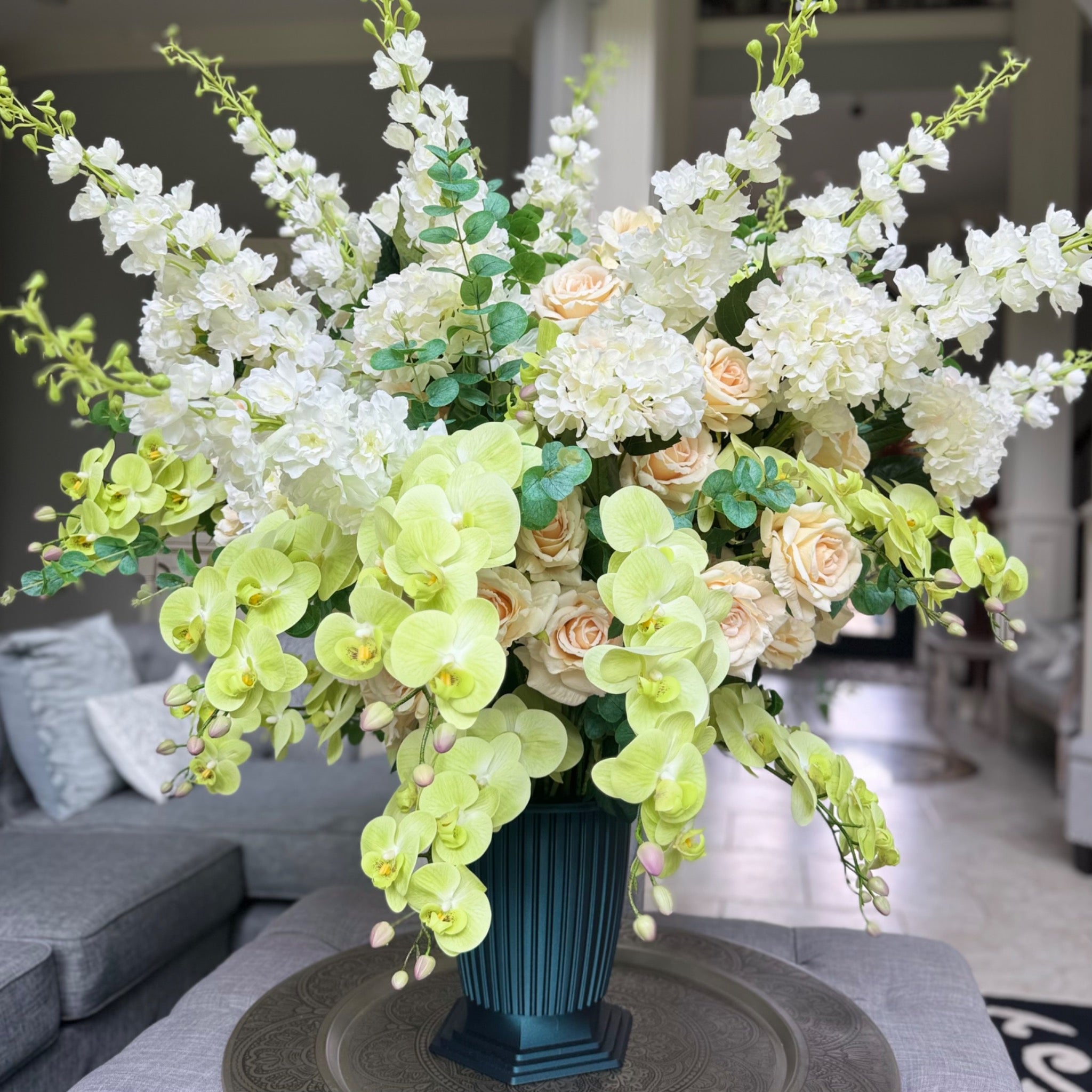 Grand Palais Premium permanent floral arrangement in the Pistachio Garden palette, displayed in the exclusive Grand Palais Bowl finished in Onyx Shimmer, featuring soft green orchids, cream roses, white hydrangeas, and white delphiniums.
