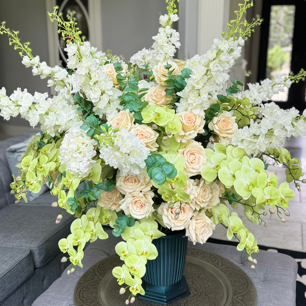 Grand Palais Premium permanent floral arrangement in the Pistachio Garden palette, featuring cascading soft green orchids, cream roses, white hydrangeas, and white delphiniums in the exclusive Grand Palais Bowl finished in Onyx Shimmer.