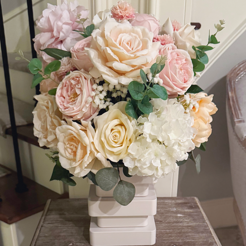 Atelier floral arrangement in the Bone White finish, Duchess size, Rosé Champagne palette displayed on a side table, featuring lifelike blush peonies, garden roses, hydrangeas, and eucalyptus.