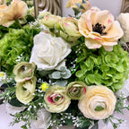 Close-up of green hydrangeas, ivory roses, cream ranunculus and soft greenery in the Signature Duchess floral arrangement.