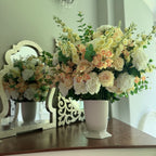 Grand Palais floral arrangement in the Bone White finish, Premium size, Peaches & Cream palette, styled on a staircase landing, featuring lifelike cream roses, peach cymbidium orchids, white peonies, blossom stems, and eucalyptus.