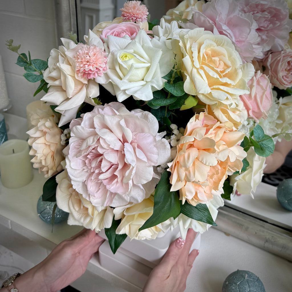 Atelier floral arrangement in the Bone White finish, Duchess size, Rosé Champagne palette, featuring lifelike blush peonies, cream and soft pink roses, peach blooms, and eucalyptus.