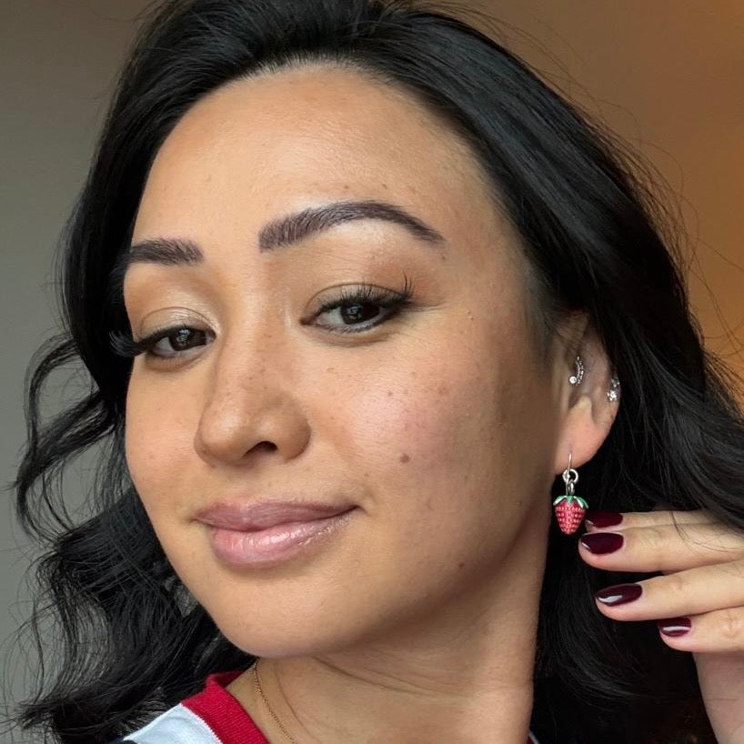 Close-up of a person wearing earrings with a neutral background