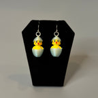Chickadee Hatching Chick earrings displayed on jewelry stand