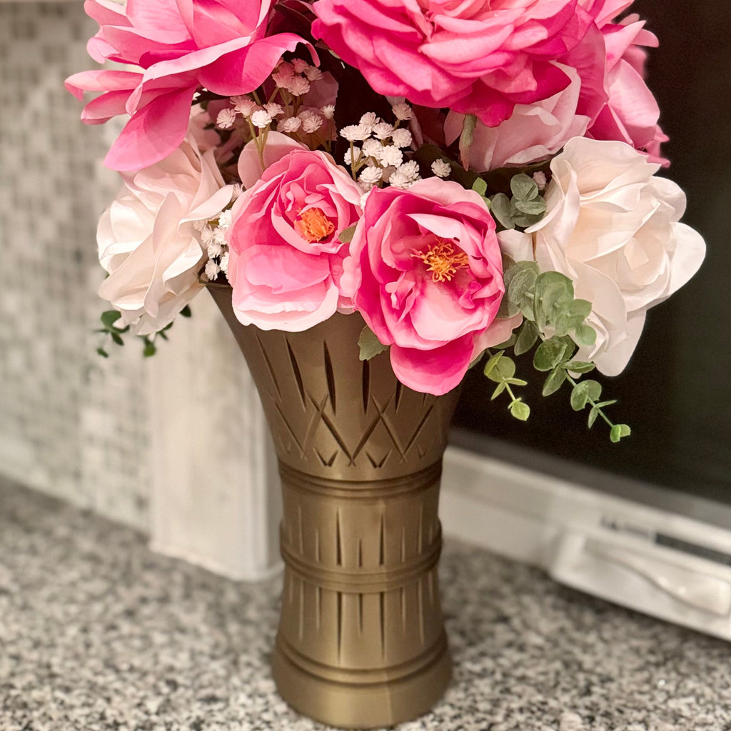 Bouquet of pink and white flowers in a bronze vase on a countertop.