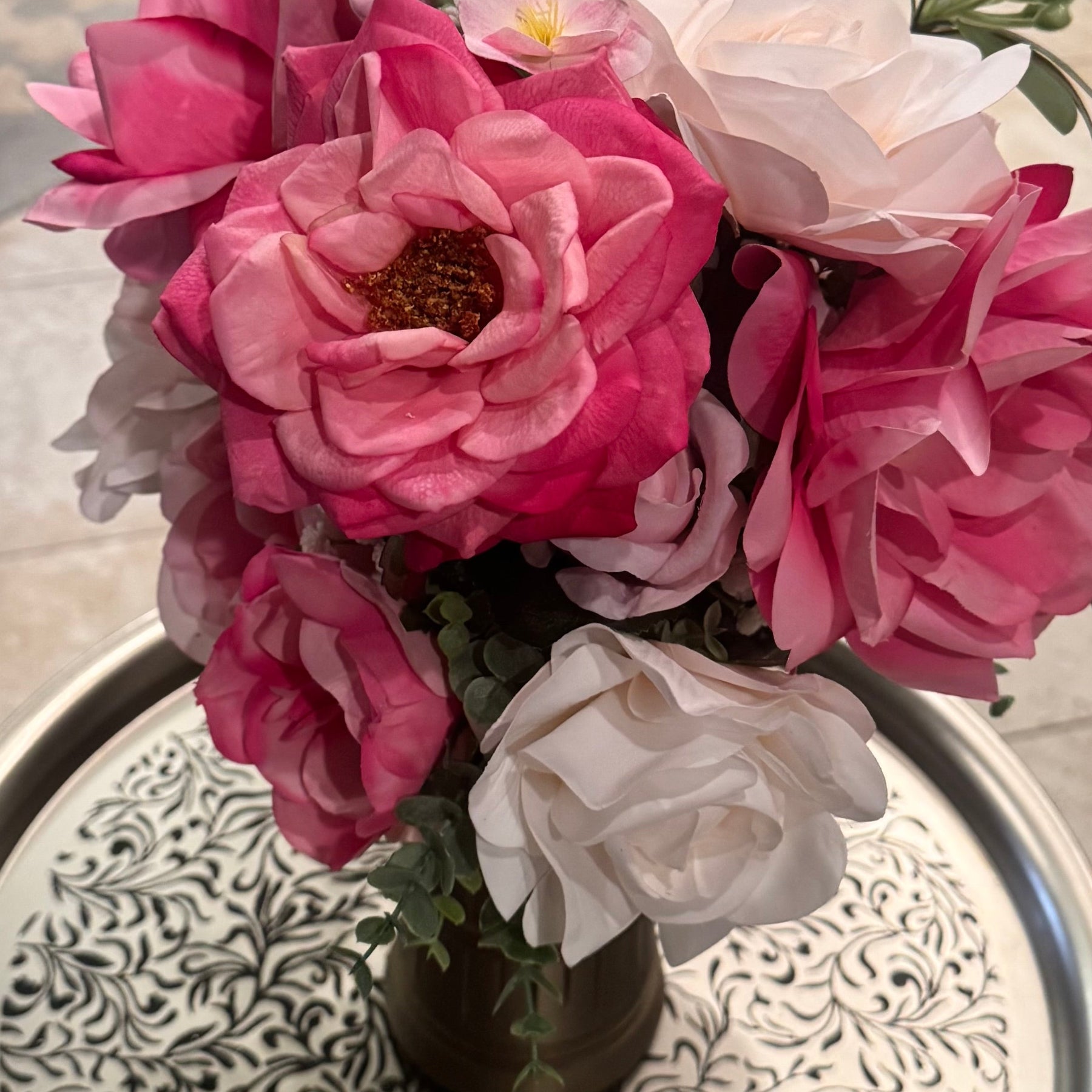Bouquet of pink and white flowers in a vase on a decorative tray.