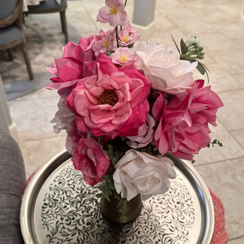 Bouquet of pink and white flowers in a vase on a decorative tray.