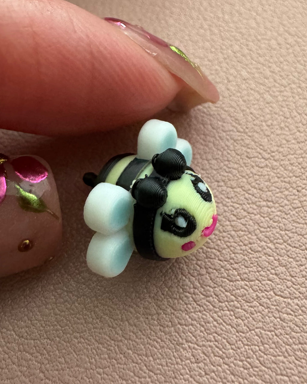 Side view close-up of Bee Happy dangle earring showing dimensional bee charm design, white wings, hand-painted details, and sterling silver hook.