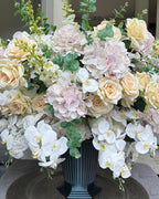 Grand Palais Platinum permanent floral arrangement featuring blush hydrangeas, ivory roses, cascading white orchids, eucalyptus greenery, and premium blooms in a black Grand Palais vessel