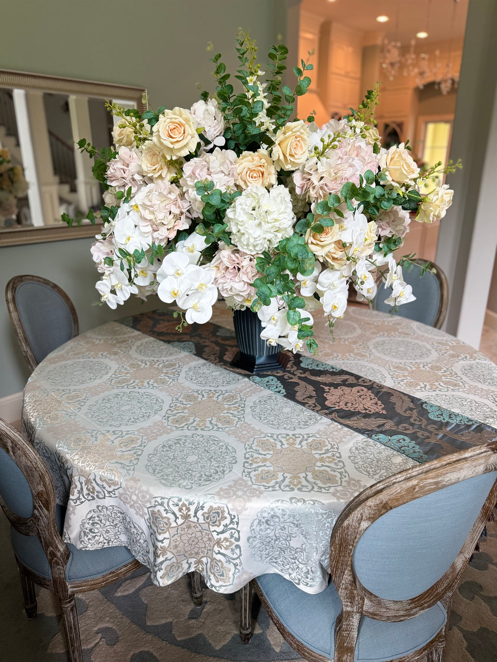 Grand Palais Platinum permanent floral arrangement displayed as a luxury dining table centerpiece featuring blush hydrangeas, ivory roses, white orchids, and eucalyptus greenery