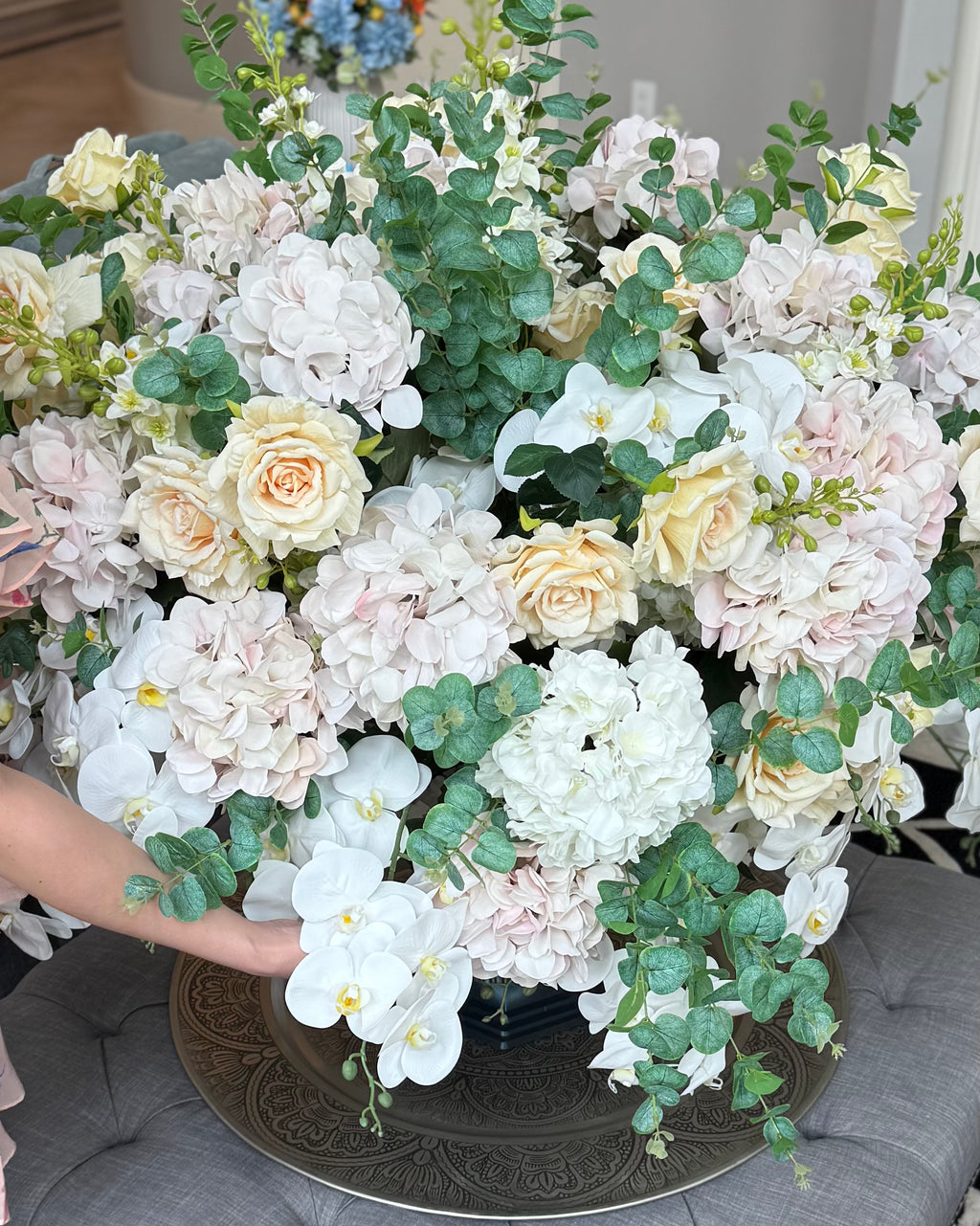 Grand Palais Platinum permanent floral arrangement featuring blush hydrangeas, ivory roses, cascading white orchids, eucalyptus greenery, and premium blooms shown for scale in a black Grand Palais vessel