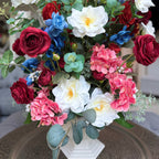 Palais Bowl floral arrangement in the Bone White finish, Queen size, Summer Soirée palette, featuring lifelike white garden roses, deep red ranunculus, blue delphiniums, pink hydrangeas, and eucalyptus.