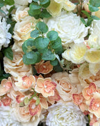 Close-up detail of the Grand Palais Premium floral arrangement in the Peaches & Cream palette, featuring lifelike ivory peonies, cream roses, peach cymbidium orchids, spray roses, and eucalyptus.