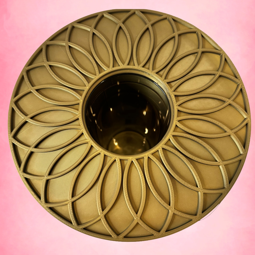 Decorative gold circular object with intricate patterns on a pink background