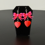 Bow heart earrings displayed on jewelry stand