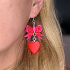 Pink bow heart earrings worn by model side profile