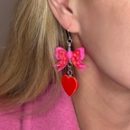 Pink bow heart earrings with sterling silver hooks worn by model