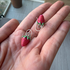 Strawberry dangle earrings displayed in hand to show size, detail, and craftsmanship.
