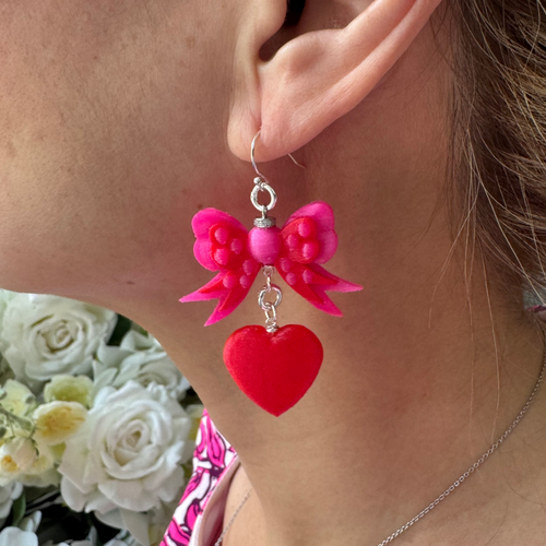 Bow & Heart Dangle Earrings with genuine 925 sterling silver hooks, featuring layered pink bows and vibrant red heart drops, worn on model.