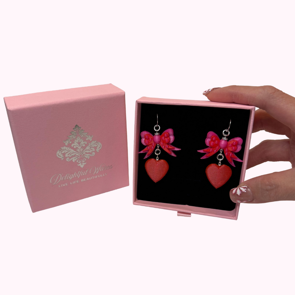 Signature Delightful Wares gift-ready jewelry box displaying the Bow & Heart Dangle Earrings.