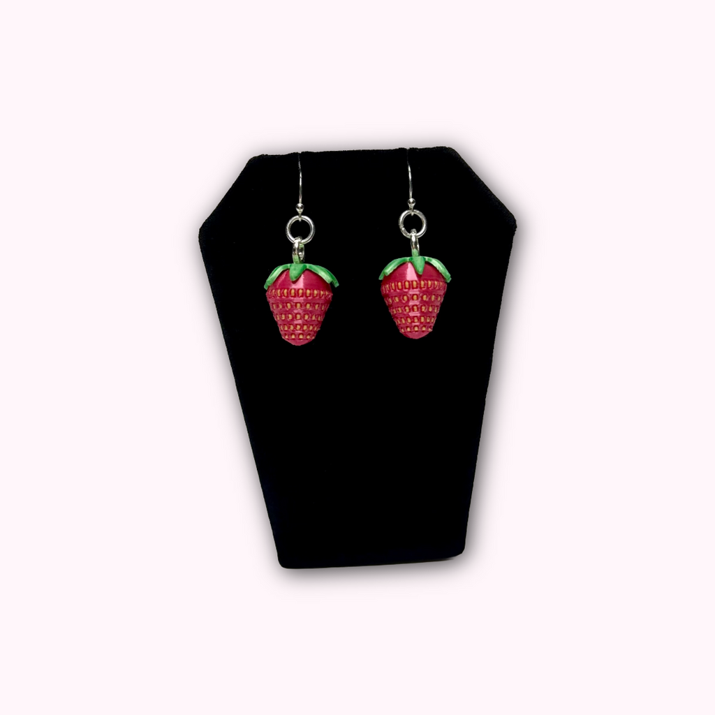 Strawberry dangle earrings displayed in hand to show size, detail, and craftsmanship.