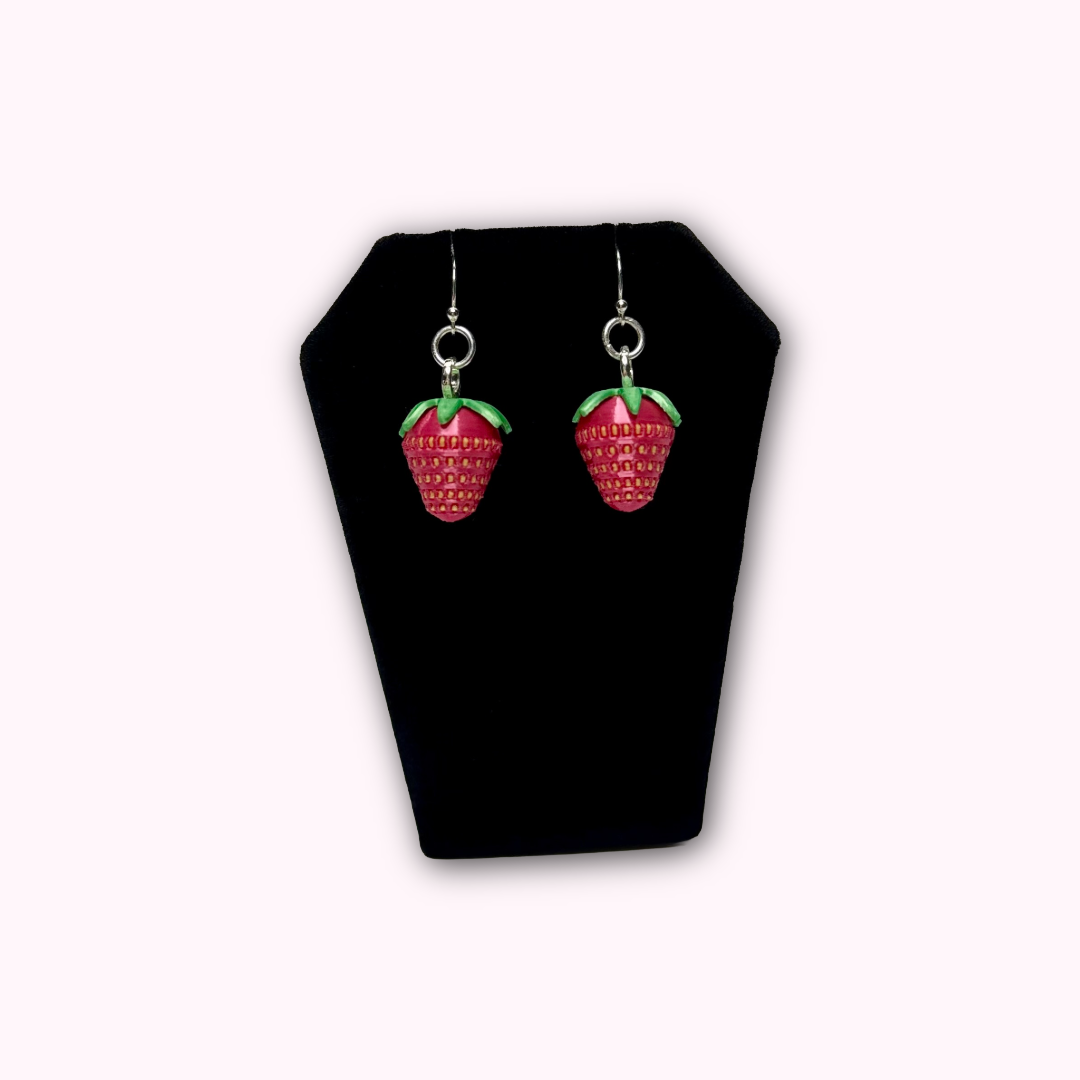 Strawberry dangle earrings displayed in hand to show size, detail, and craftsmanship.