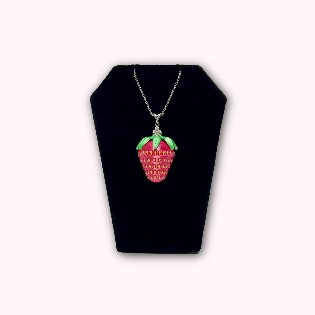 Strawberry pendant necklace with sterling silver chain displayed on a black jewelry stand.