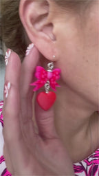 Video showcasing Bow & Heart Dangle Earrings with genuine 925 sterling silver hooks, featuring layered pink bows and red heart drops, worn on model and presented in signature gift-ready packaging.