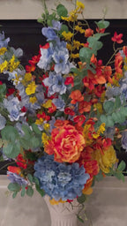 Video showcasing the Signature Collection Bouquet Vase arrangement in the Sunset Meadow palette, featuring lifelike blue hydrangeas, vibrant orange and yellow blooms, eucalyptus, and the Signature Collection Bouquet Vase in the Bone White finish.
