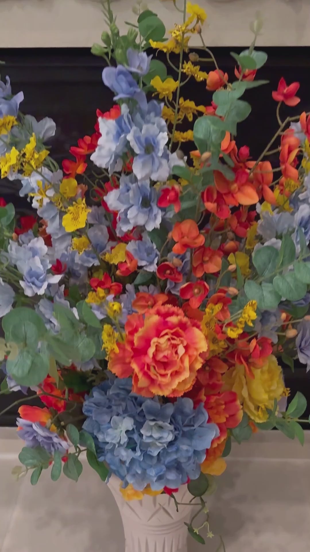 Video showcasing the Signature Collection Bouquet Vase arrangement in the Sunset Meadow palette, featuring lifelike blue hydrangeas, vibrant orange and yellow blooms, eucalyptus, and the Signature Collection Bouquet Vase in the Bone White finish.