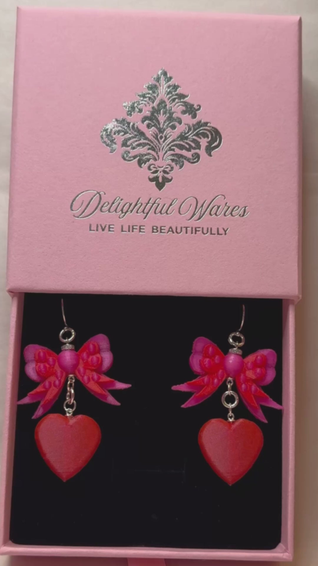 Video showcasing Bow & Heart Dangle Earrings with genuine 925 sterling silver hooks, presented in a signature Delightful Wares gift-ready jewelry box and highlighting the earrings' layered bow and vibrant heart design.